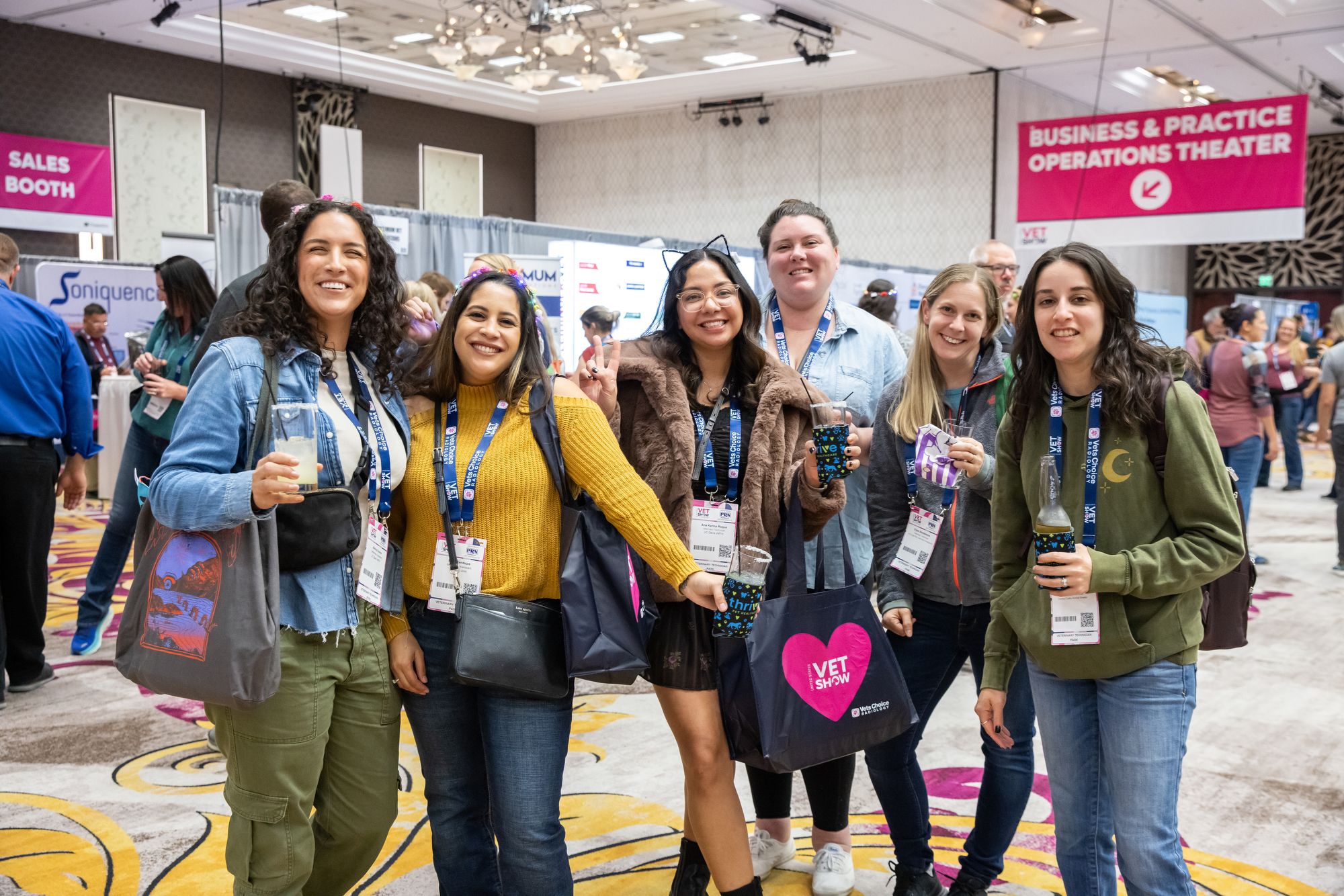 A group of attendees in a line smiling and holding drinks